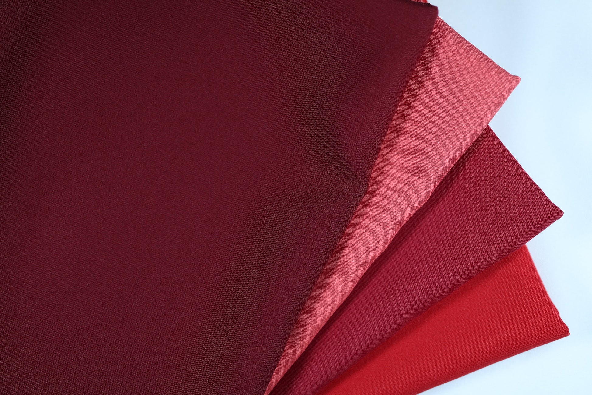 Polyester Panama Stoffe in Weinrot- und Rot-Tönen – nebeneinandergelegt von Weinrot über Rot bis hin zu strukturiertem Rot für elegante Farbvergleiche bei Dekostoffen