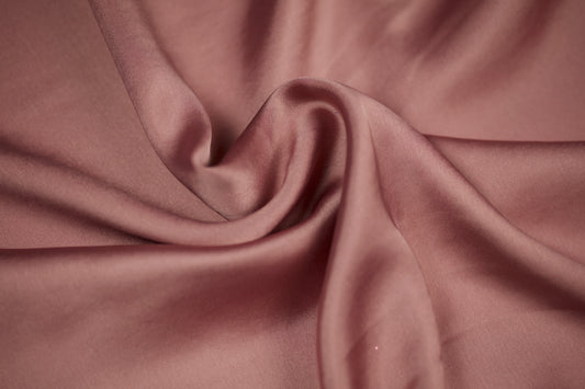 Nahaufnahme eines luxuriösen Satinstoffs in roséfarbenem Altrosa mit edlem Glanz und weichem Faltenwurf – perfekt für elegante Nähideen.
